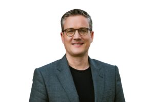 Sebastian Bluhm Portraitbild mit grauem Sakko und schwarzem T-Shirt freigestellt